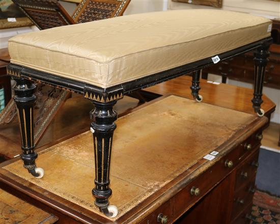 A Victorian ebonised and gilt decorated dressing stool, on turned fluted legs W.114cm